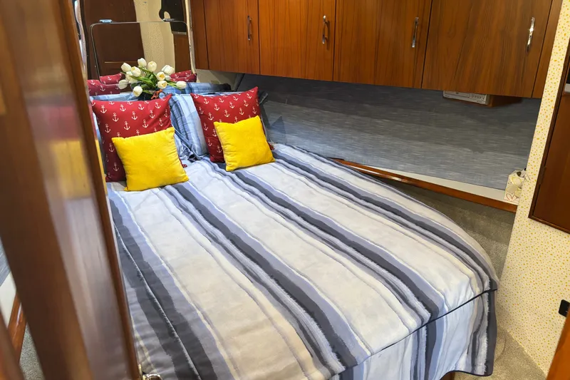 Slide: The Image of Cozy bedroom in 1995 Ocean 48 Cockpit Motor Yacht with striped bedding and colorful pillows. - 28