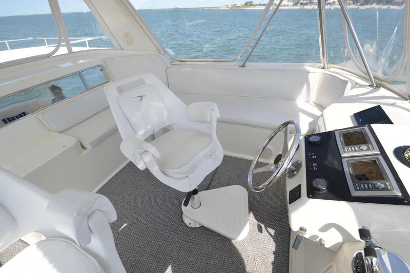 Slide: The Image of 1995 Ocean 48 Cockpit Motor Yacht helm with white captain's chair and steering wheel. - 77