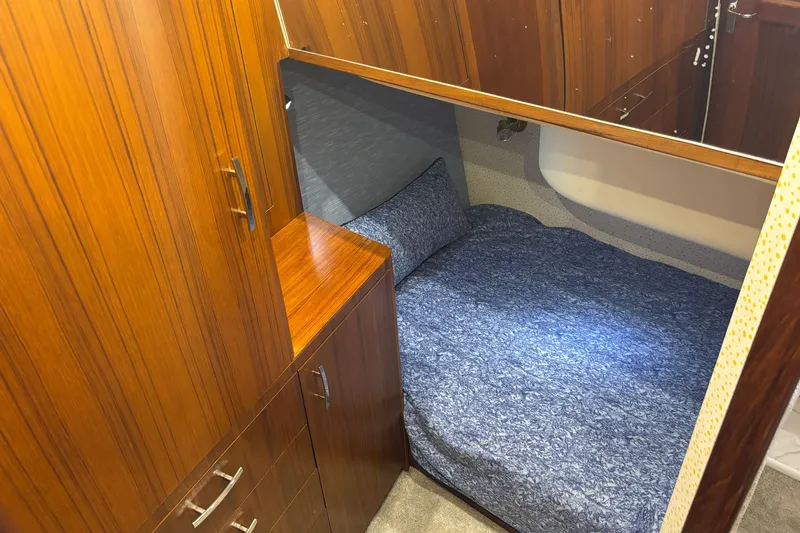 Slide: The Image of Cozy cabin interior of 1995 Ocean 48 Cockpit Motor Yacht with wooden cabinetry and blue bedding. - 33