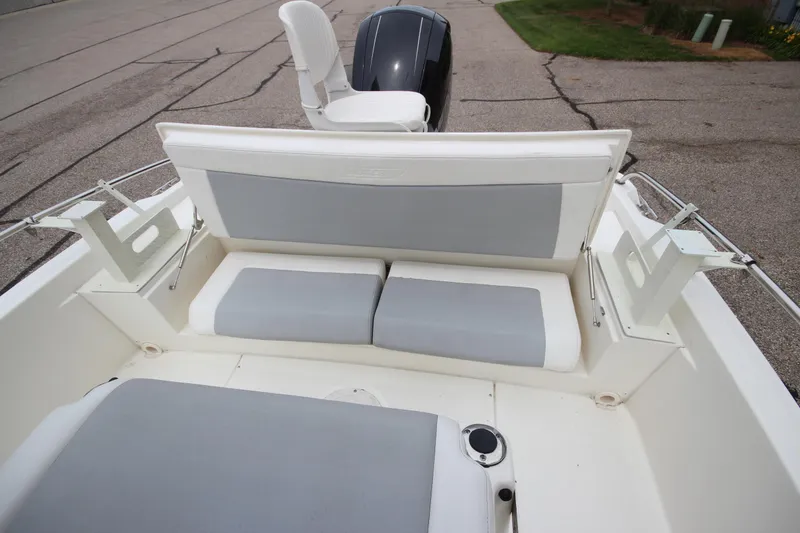 Slide: The Image of 2014 Boston Whaler 210 Dauntless boat interior with cushioned seating and motor view. - 18