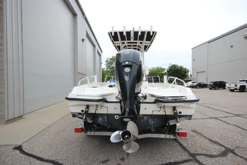 Slide: The Image of 2014 Boston Whaler 210 Dauntless boat with outboard motor, parked near industrial buildings. - 2