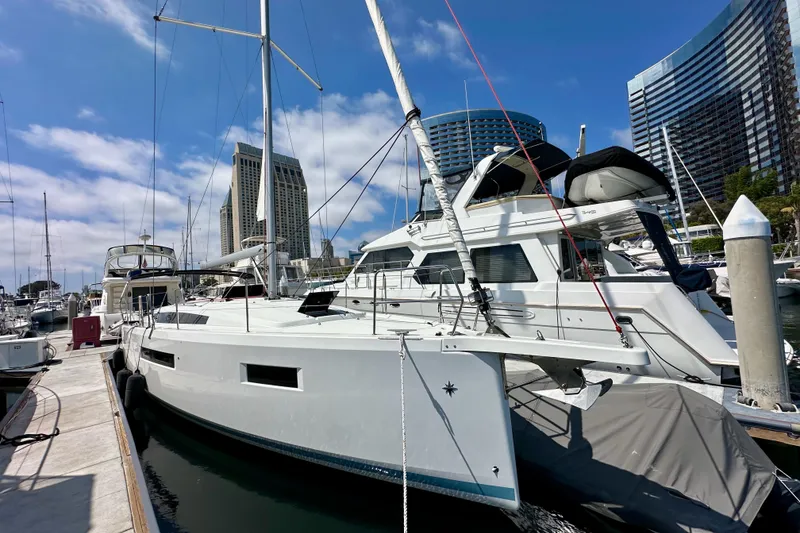 Slide: The Image of 2024 Jeanneau Sun Odyssey 410 sailboat docked in a marina with modern buildings in the background. - 5