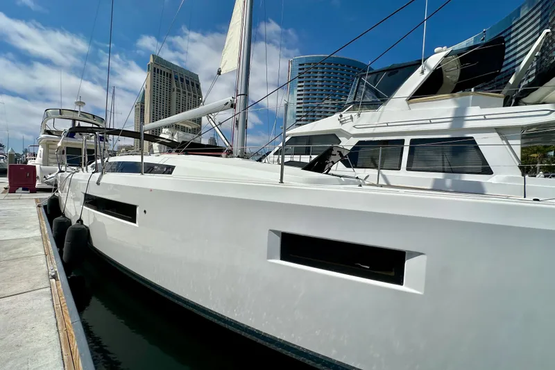 Slide: The Image of 2024 Jeanneau Sun Odyssey 410 yacht docked at marina, modern design, clear sky background. - 8