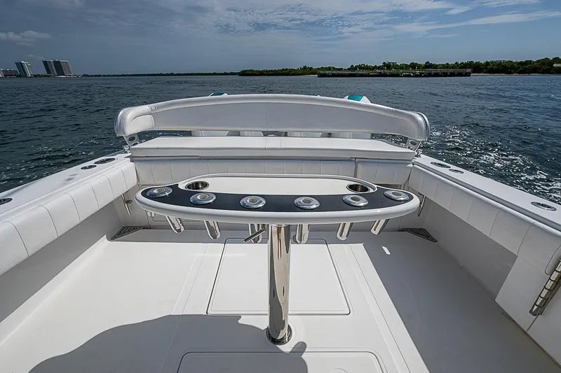 Slide: The Image of 2020 Bahama 41 boat deck with rod holders, overlooking calm waters and distant buildings. - 20