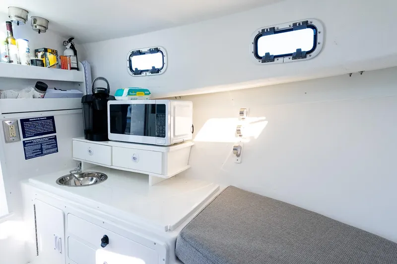 Slide: The Image of 2024 Steiger Craft 31 Fisherman interior with kitchenette, microwave, and seating area. - 46