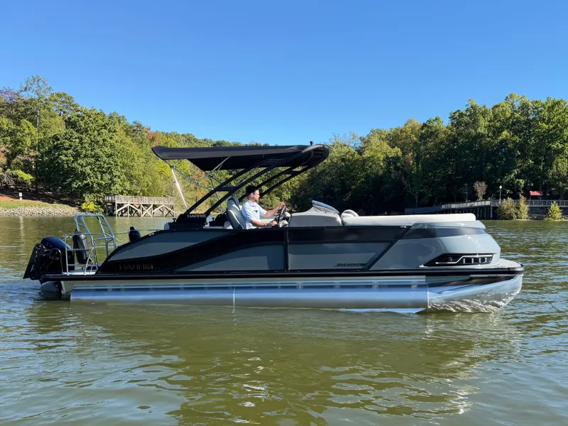 Slide: The Image of A modern pontoon boat with a black canopy cruises on a calm lake, surrounded by trees. - 6