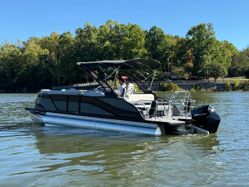 Slide: The Image of 2027 Harris Grand Mariner 230 on a calm lake with trees in the background. - 1