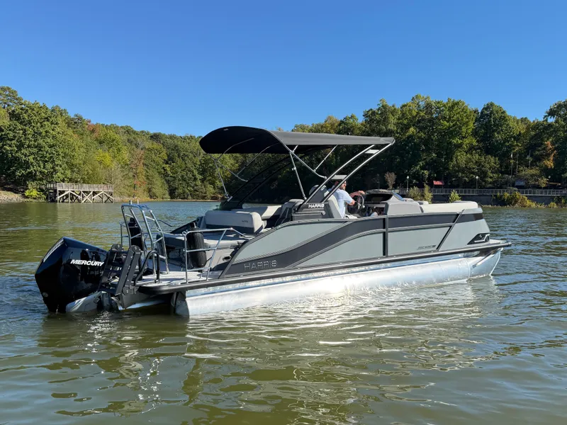Slide: The Image of A sleek pontoon boat with a black canopy on a calm lake, surrounded by trees. - 5