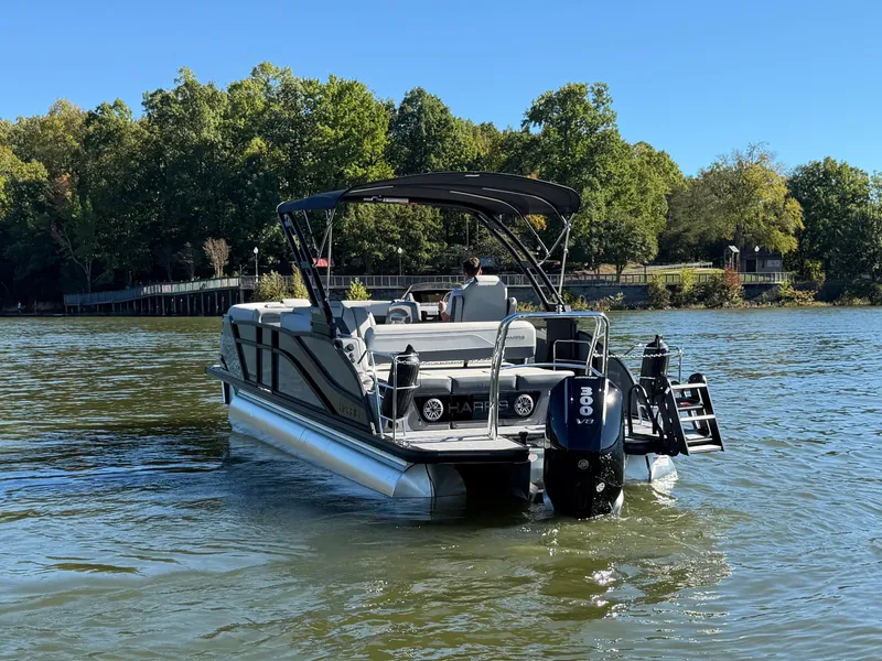 Slide: The Image of A Harris Grand Mariner 230 pontoon boat on a calm lake with a wooded shoreline. - 2