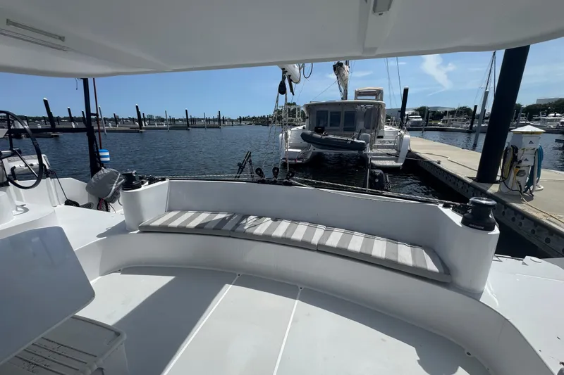 Slide: The Image of 2023 Schionning Arrow 1280S catamaran docked at a marina, featuring spacious seating area. - 13