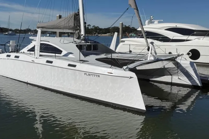 Slide: The Image of 2023 Schionning Arrow 1280S catamaran docked in a marina, reflecting on calm water. - 4