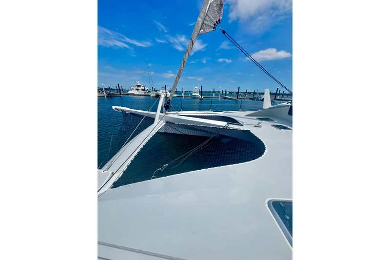 Slide: The Image of 2023 Schionning Arrow 1280S catamaran docked at marina under blue sky. - 6