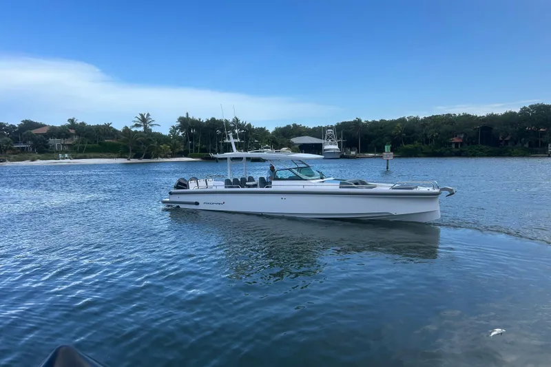 Slide: The Image of 2024 Axopar 37 Sun-Top boat cruising on a serene waterway with lush greenery. - 1