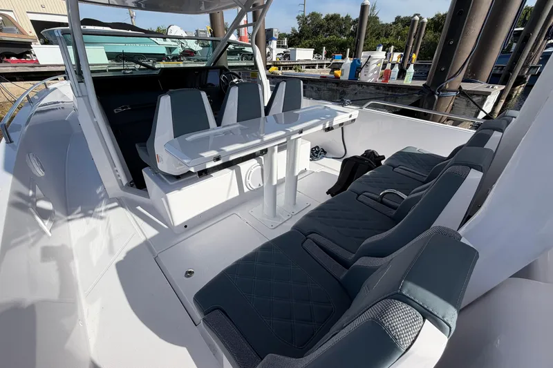 Slide: The Image of 2024 Axopar 37 Sun-Top boat interior with seating and table, docked at marina. - 10