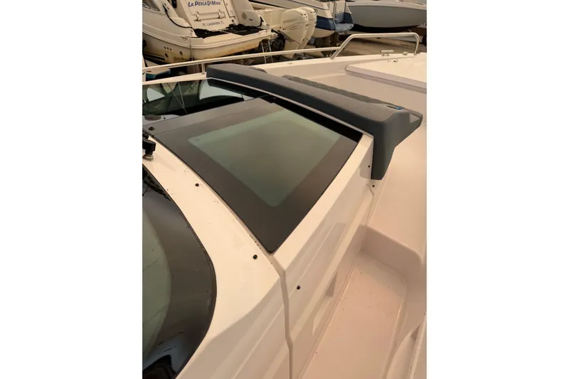 Slide: The Image of 2024 Axopar 37 Sun-Top boat with sleek windshield design in marina setting. - 13