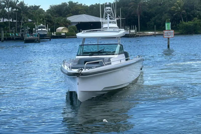 Slide: The Image of 2024 Axopar 37 Sun-Top boat cruising on a calm waterway with lush greenery. - 3