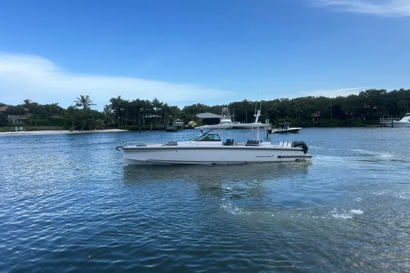 The Image of 2024 Axopar 37 Sun-Top boat cruising on a scenic waterway with lush greenery. - 0