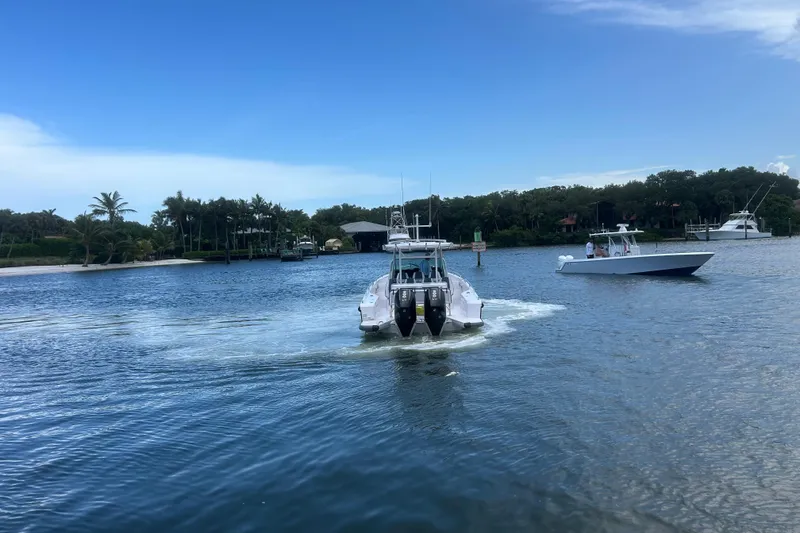 Slide: The Image of 2024 Axopar 37 Sun-Top cruising on a scenic waterway with other boats nearby. - 5