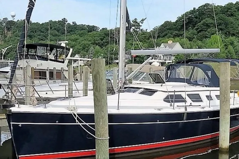 Slide: The Image of 2007 Hunter 41 Deck Salon sailboat docked at a marina, surrounded by lush greenery. - 4