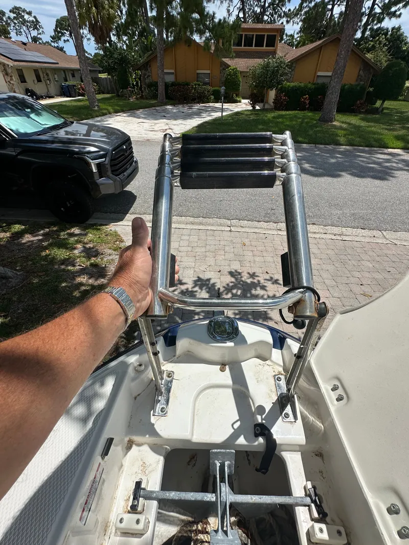 Slide: The Image of A hand holds a ladder on a boat. Houses and a car are visible in the background. - 19