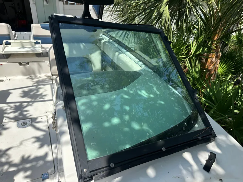 Slide: The Image of A 2017 Chaparral 243VRX with a clear windshield and white seating, surrounded by palm trees. - 25