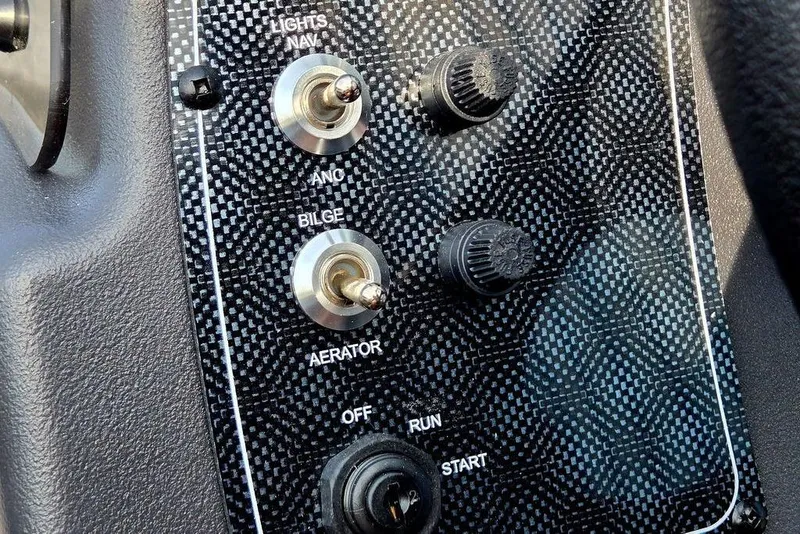 Slide: The Image of Control panel of 2026 Tracker Bass Tracker Classic XL boat with switches and knobs. - 12