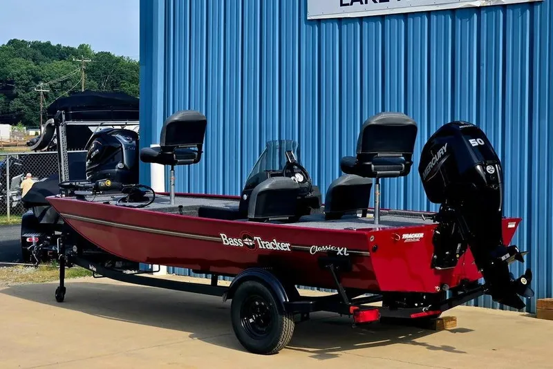 Slide: The Image of 2026 Tracker Bass Tracker Classic XL boat, red, parked outside a blue building. - 4