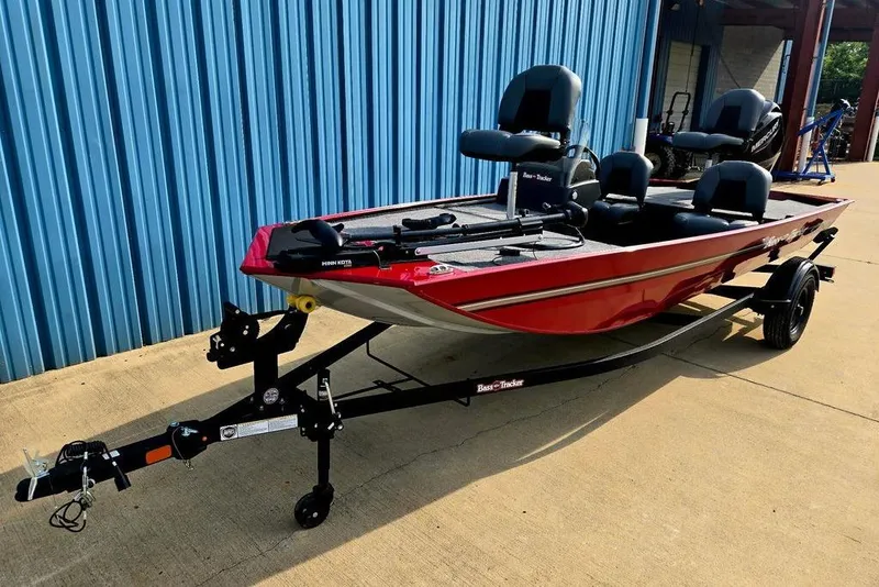 Slide: The Image of 2026 Tracker Bass Tracker Classic XL boat in red, parked on a trailer by a blue wall. - 7