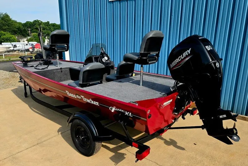 Slide: The Image of 2026 Tracker Bass Tracker Classic XL boat with Mercury engine, parked by a blue building. - 35