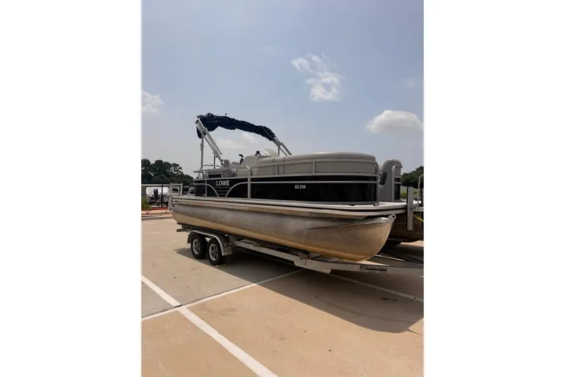 Slide: The Image of 2021 Lowe SS 210 pontoon boat on trailer under clear sky. - 0