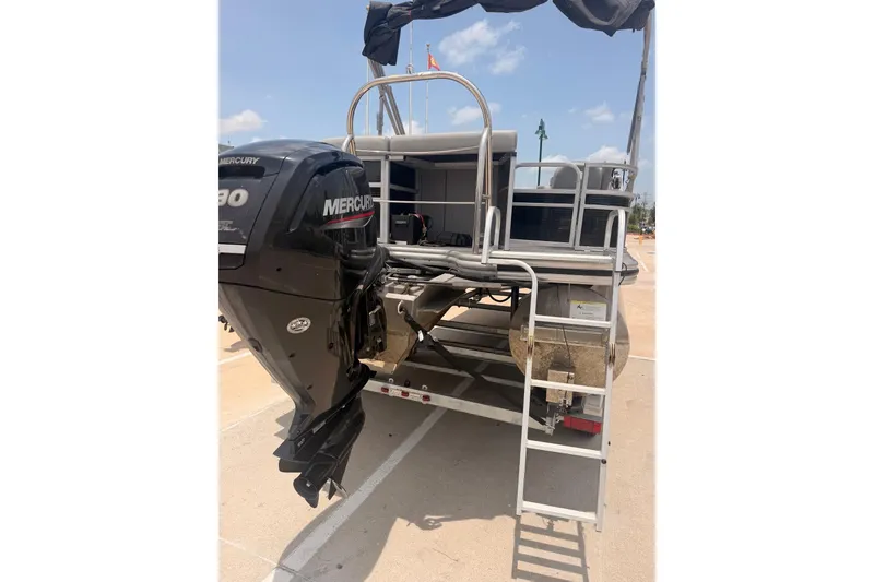 Slide: The Image of 2021 Lowe SS 210 pontoon boat with Mercury outboard motor, docked under clear skies. - 14