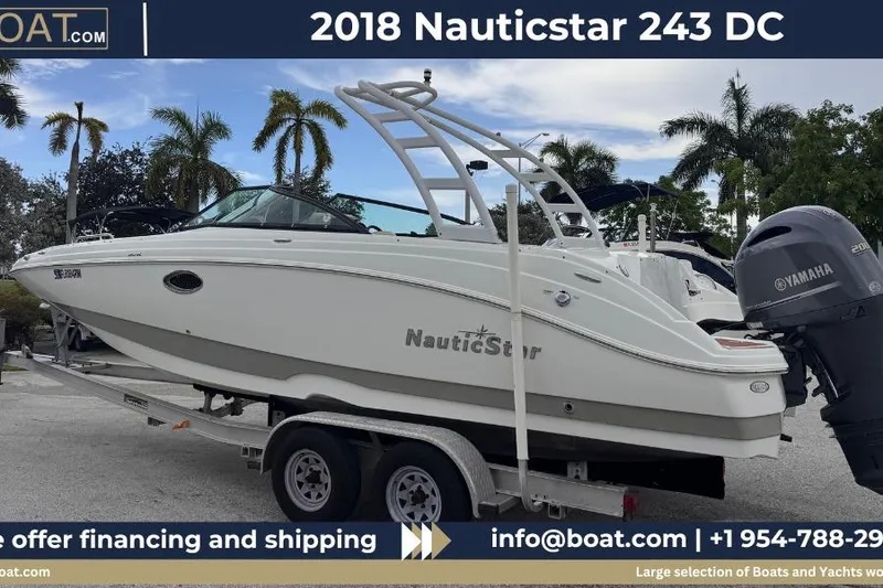 The Image of 2018 NauticStar 243DC Sport Deck boat on trailer with Yamaha engine, palm trees in background. - 0