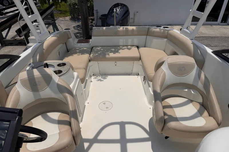 Slide: The Image of 2018 NauticStar 243DC Sport Deck interior with beige seating and cup holders. - 12