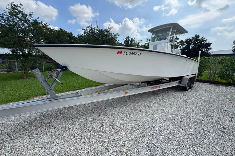 The Image of 2022 Rambo 27 boat on trailer, parked on gravel with trees in background. - 0