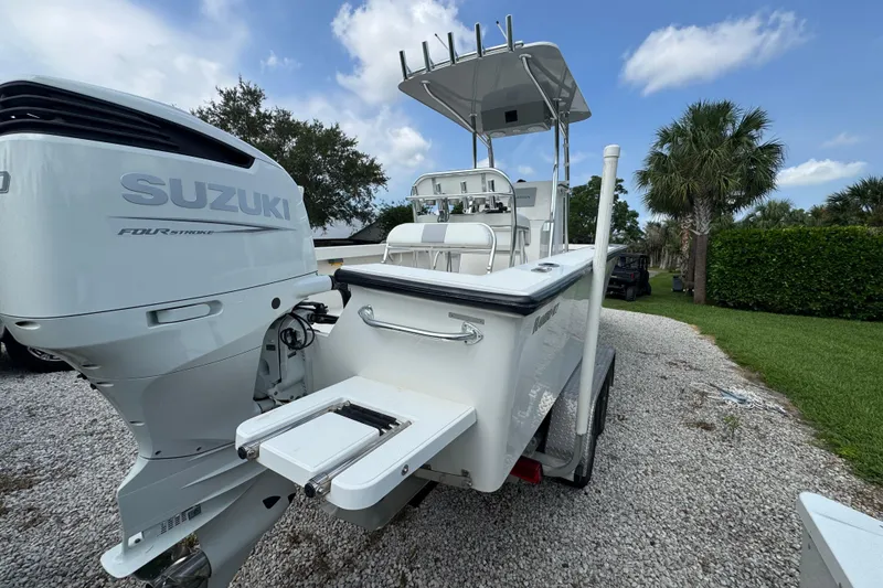 Slide: The Image of 2022 Rambo 27 boat with Suzuki four-stroke engine, parked on gravel driveway. - 14