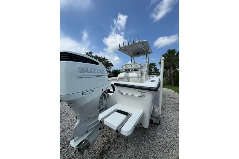 Slide: The Image of Rambo 27 boat (2022) with Suzuki engine, parked on gravel under a blue sky. - 15