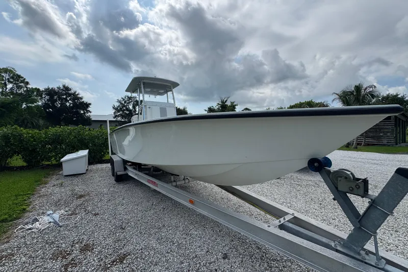 Slide: The Image of 2022 Rambo 27 boat on trailer, parked on gravel driveway under cloudy sky. - 19