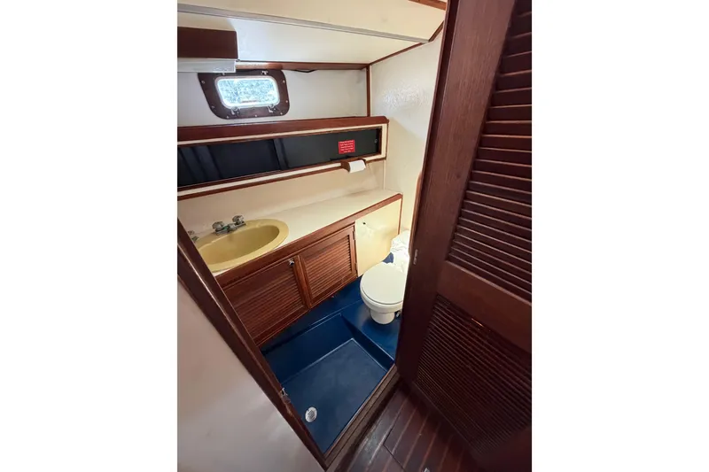Slide: The Image of 1977 Morgan Out Island 51 yacht bathroom with wooden cabinets and a yellow sink. - 45
