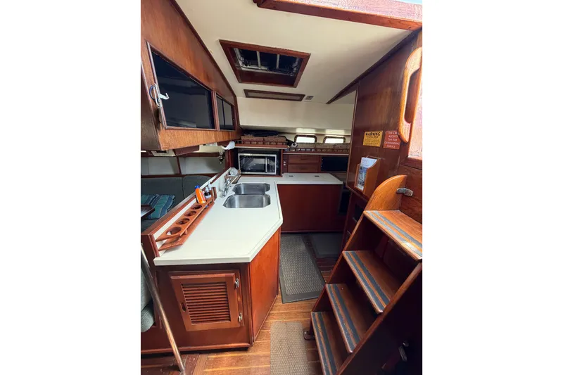 Slide: The Image of 1977 Morgan Out Island 51 yacht interior with wooden cabinetry and compact kitchen area. - 30