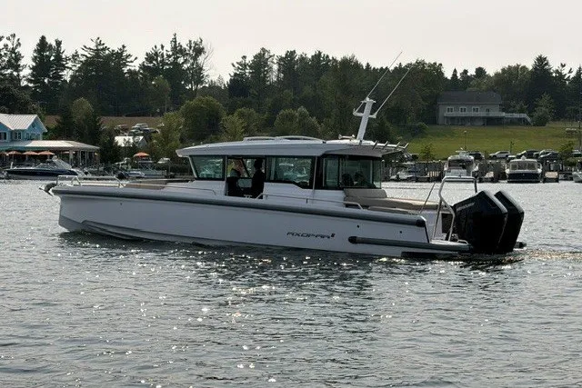 The Image of 2024 Axopar 37 XC Cross Cabin boat cruising on a scenic lake. - 0