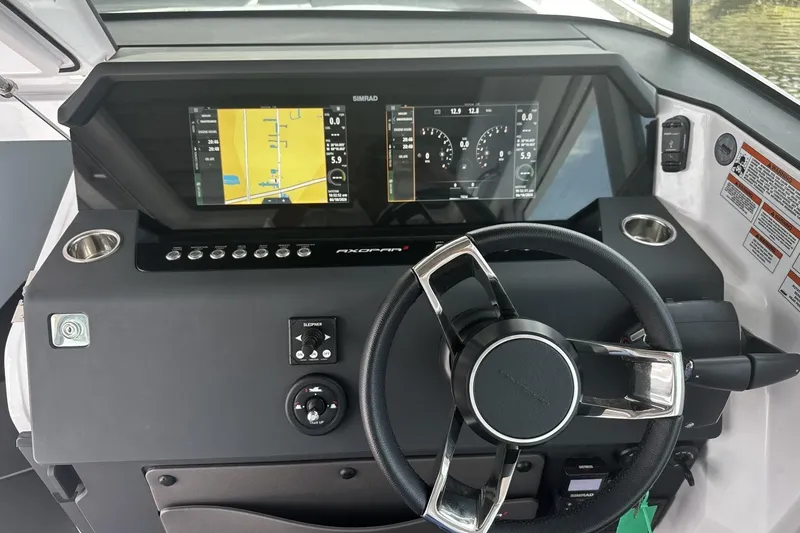 Slide: The Image of 2024 Axopar 37 XC Cross Cabin dashboard with dual Simrad displays and steering wheel. - 6