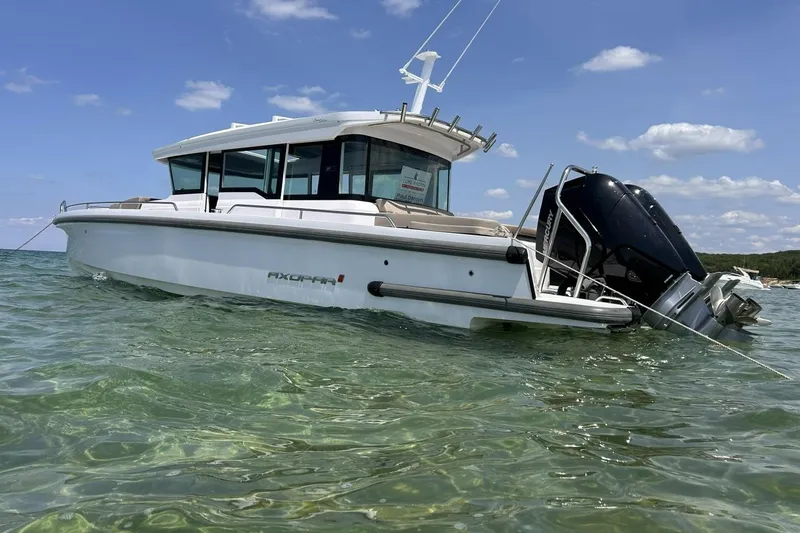 The Image of 2024 Axopar 37 XC Cross Cabin boat anchored in clear water under a blue sky. - 1