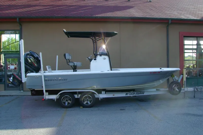 The Image of 2022 NauticStar 227 XTS boat on trailer, parked outside a building. - 1