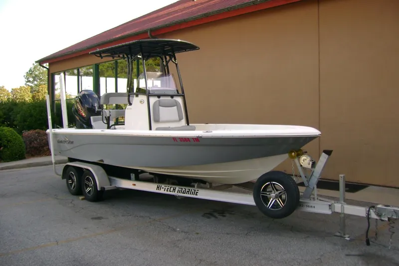 Slide: The Image of 2022 NauticStar 227 XTS boat on trailer, parked outdoors near a building. - 2