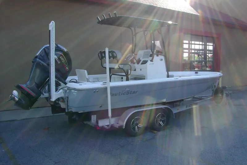 Slide: The Image of 2022 NauticStar 227 XTS boat on trailer, parked outdoors with sunlight reflections. - 6