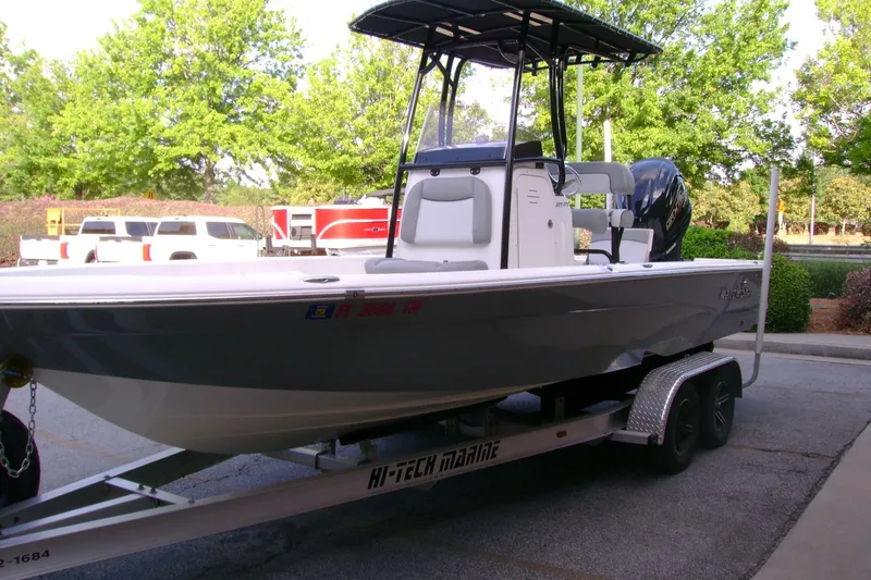 Slide: The Image of 2022 NauticStar 227 XTS boat on trailer, parked outdoors with trees in background. - 7