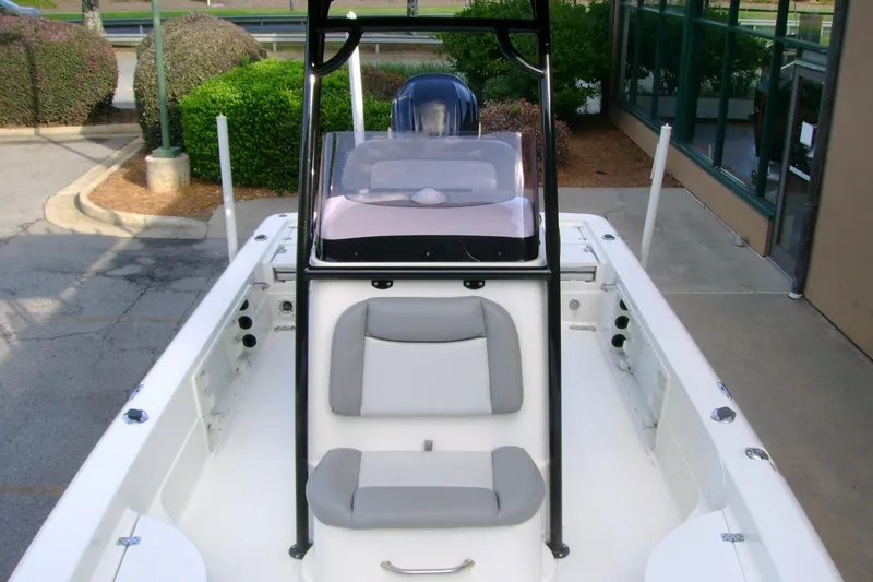 Slide: The Image of 2022 NauticStar 227 XTS boat interior with seating and console, parked outdoors. - 8