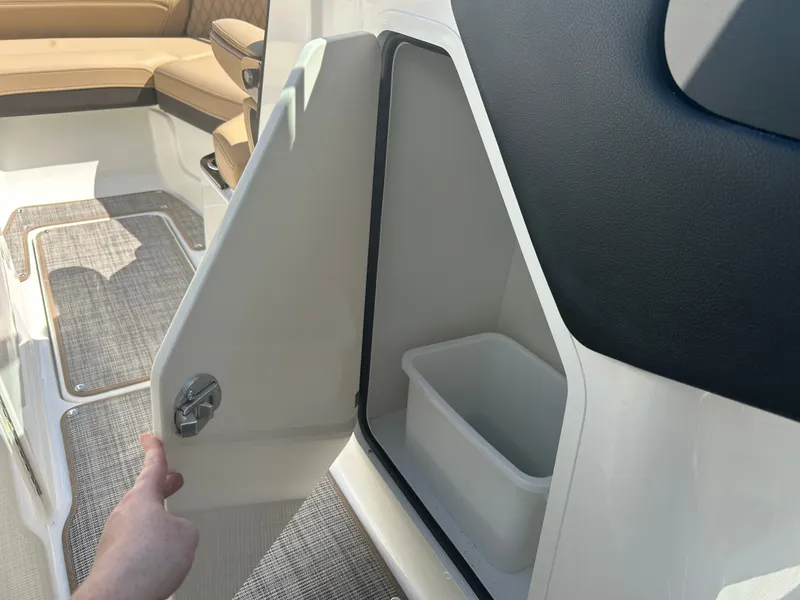 Slide: The Image of An open storage compartment on a 2027 Sea Ray SLX 260 boat with a trash bin inside. - 40