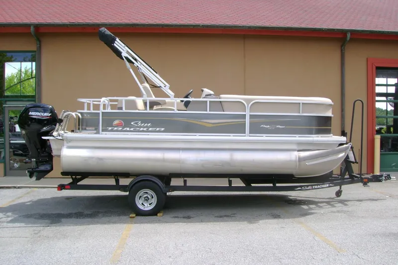 The Image of 2025 Sun Tracker Party Barge 18 DLX pontoon boat on trailer, parked outdoors. - 1