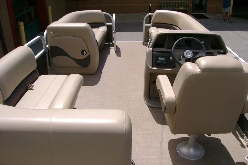 Slide: The Image of 2025 Sun Tracker Party Barge 18 DLX interior with beige seating and steering console. - 11